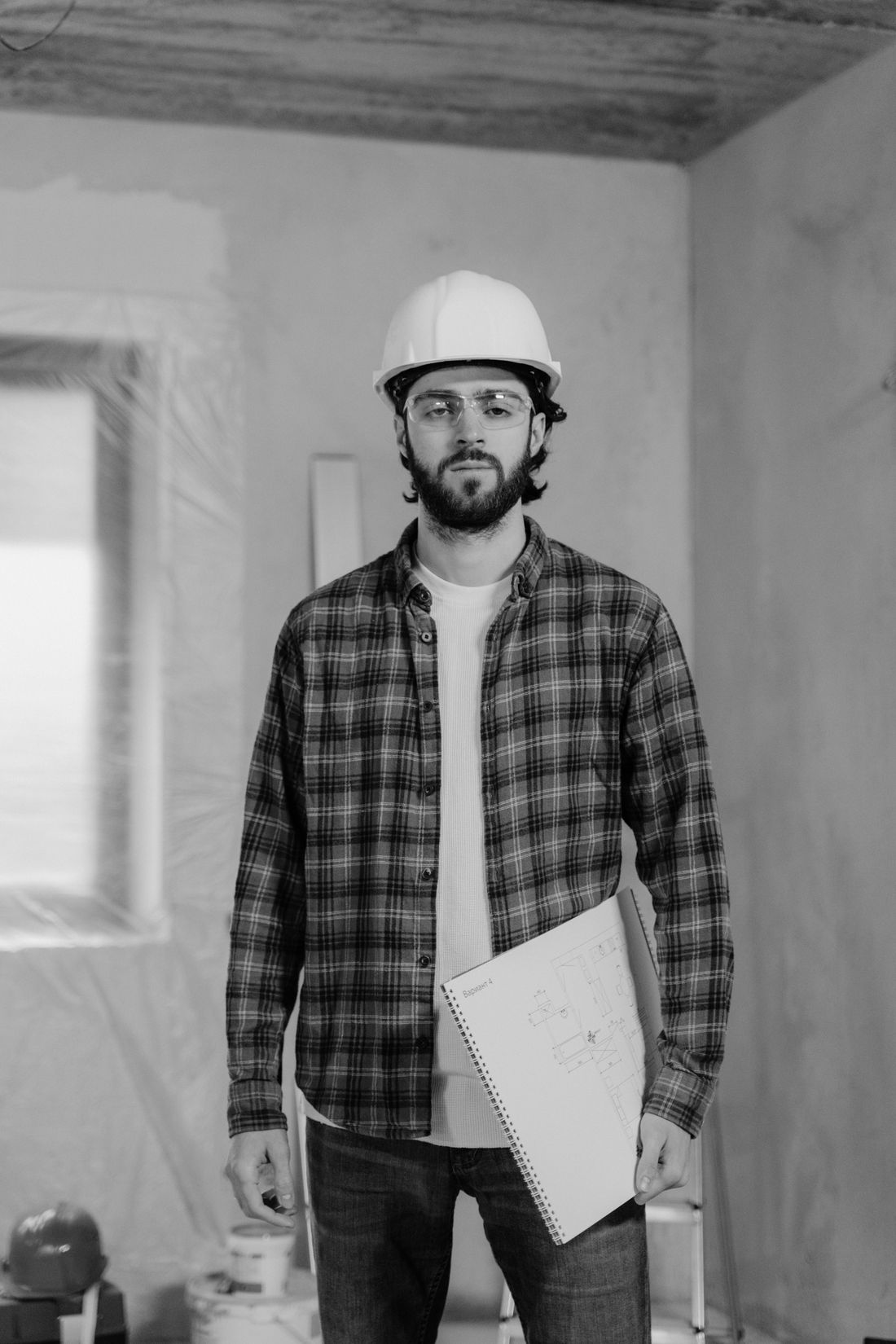 Site inspector in a hard hat writing on a clipboard while reviewing site documents