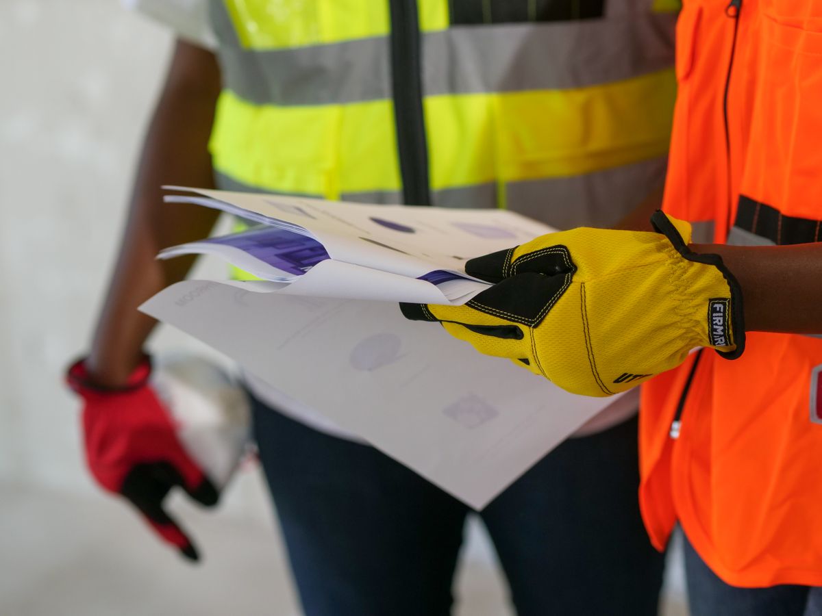 Construction worker in a hi-vis vest handing over site documents on a building project